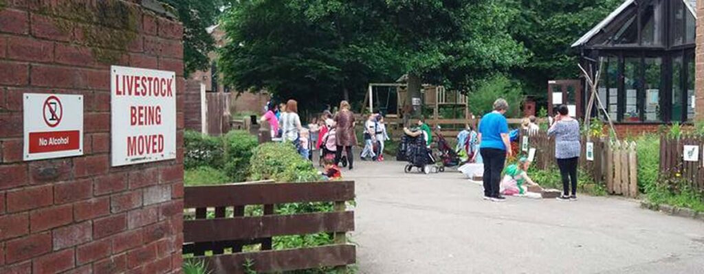 Visitors enjoying the day at Rice Lane farm, rustic fences and shrubbery stretch into the distance.