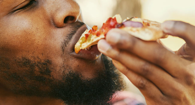 A man enjoying a slice of pizza.