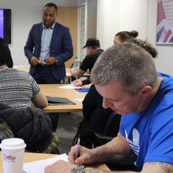 A guest speaker at our Next Steps Centre talking to a room of seated learners who are taking notes.