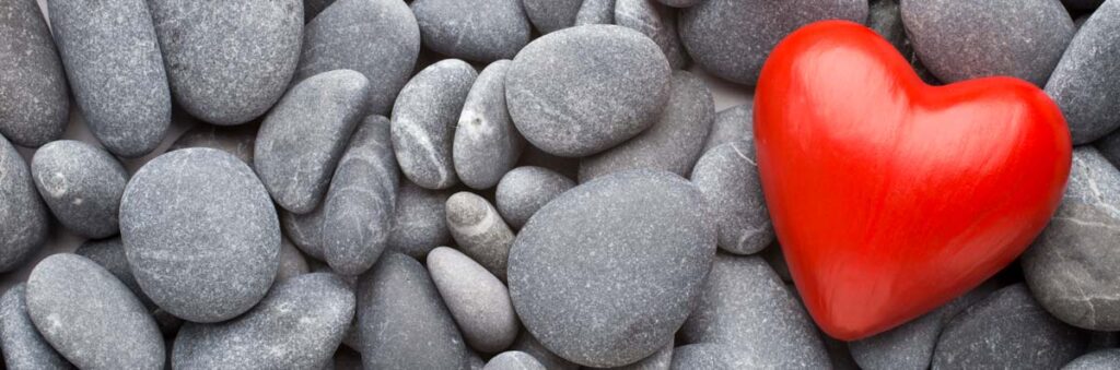 A close-up of pebbles with a bright red heart placed amongst them.