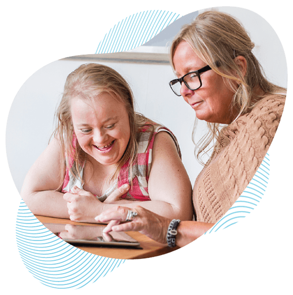 A woman who uses support services and a support worker interact happily over a tablet device.