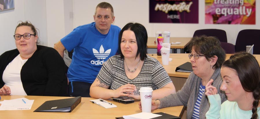 A group of Next Steps learners listening to a presentation.