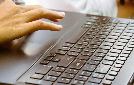 A hand using the trackpad on a laptop.