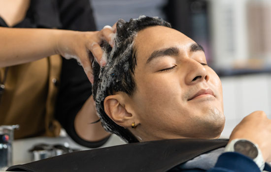 A young man having his head shampooed in a salon.