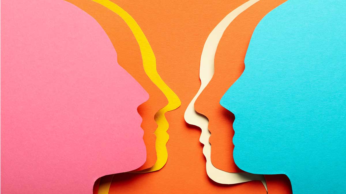 A graphic of layered paper head silhouettes in pink, blue and yellow, facing each other on an orange background, representing communication.