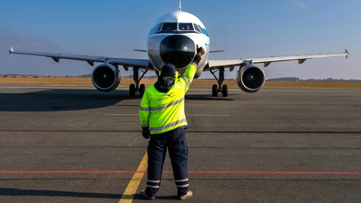 Airport steward directs air traffic on runway.
