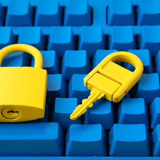 A blue computer keyboard with a yellow padlock and key placed on top.